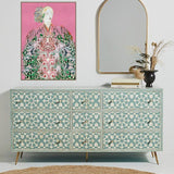 Patterned dresser with a mirror and  boho women artwork on a white wall