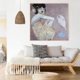 Living room with a sofa, decorative pillows, and a framed artwork of girl with bird art print on the wall.