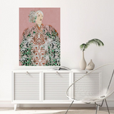 Framed artwork of a woman with a pink background on a white wall above a white cabinet.