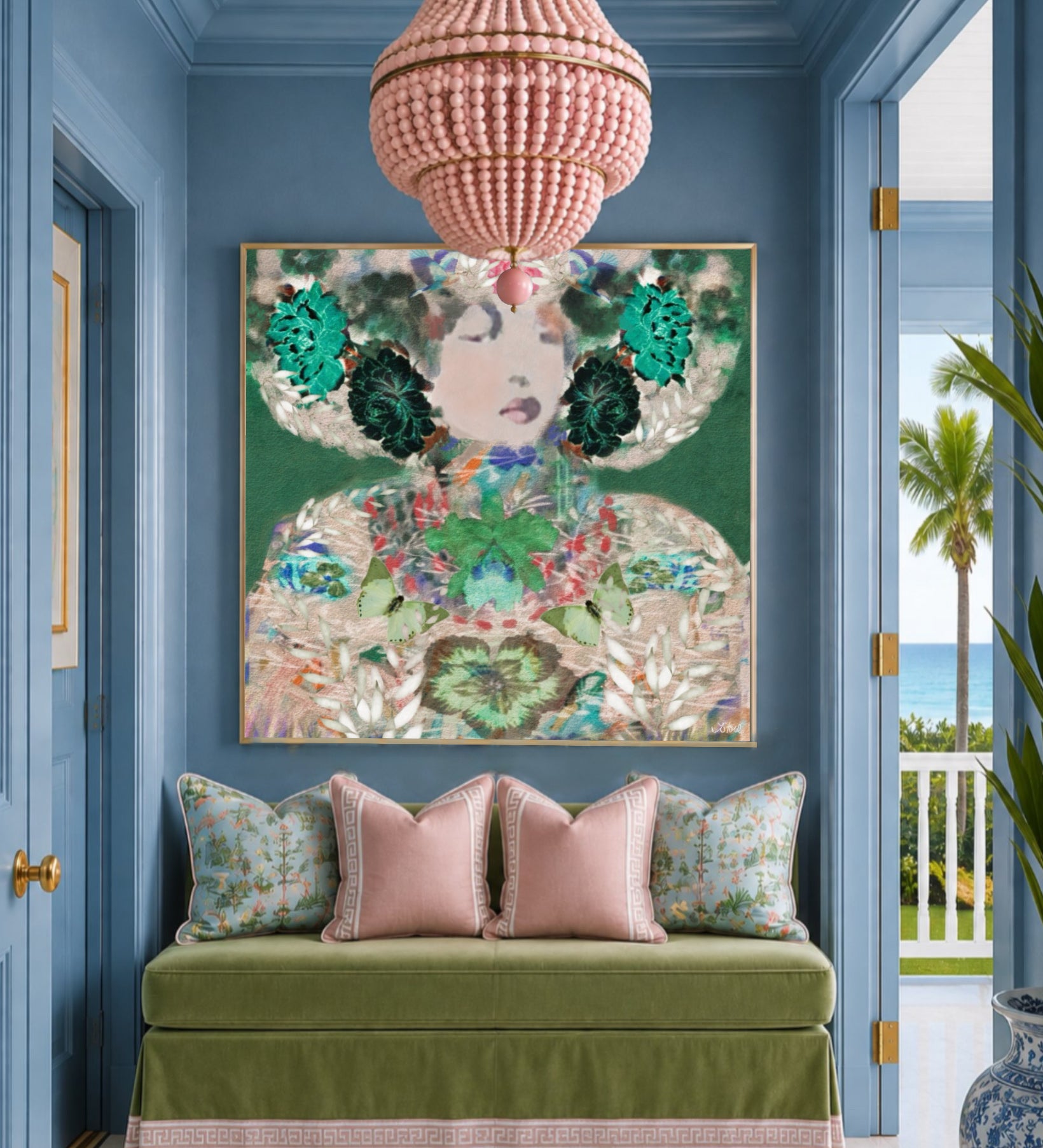 A large framed art print featuring a colorful, ornate portrait with green floral elements and gold detailing, displayed on a blue wall above a green velvet bench with pink pillows in a styled interior.