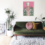 Boho women art print above Green sofa with pink and brown cushions in a living room setting.